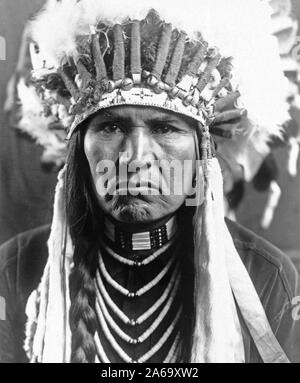 Edward S. Curtis indiens des États-Unis - Nez Percé l'homme en pleine plume coiffure, cheveux tressés, colliers et ca. 1910 Banque D'Images