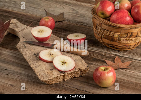 Pommes en tranches sur une planche à découper en bois sur une table décorée avec des feuilles d'automne Banque D'Images