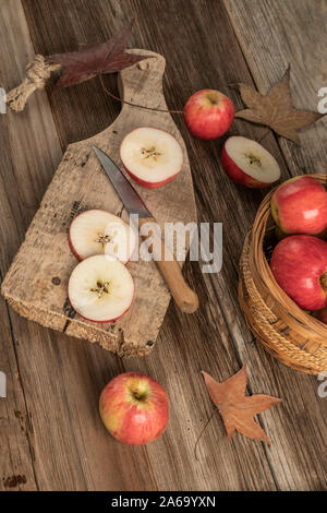 Pommes en tranches sur une planche à découper en bois sur une table décorée avec des feuilles d'automne Banque D'Images