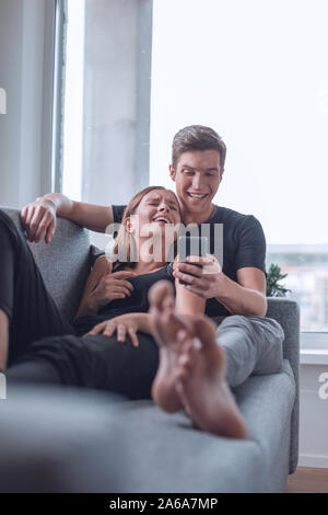 Jeune couple aimant parcourir des photos sur leur smartphone Banque D'Images