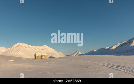 Petite cabine dans le paysage d'hiver de l'Arctique avec des montagnes enneigées sur Svalbard, Norvège Banque D'Images