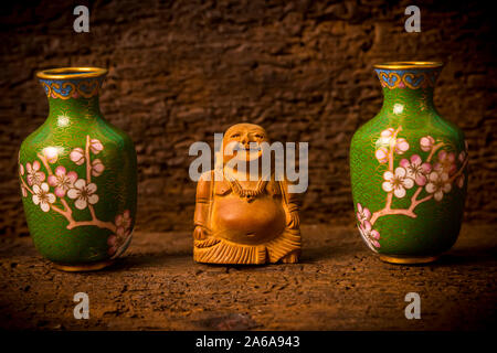 Figurine en bois spirituelle Budai Maitreya entre vert foncé sur vases ornementaux du plateau au sol Banque D'Images