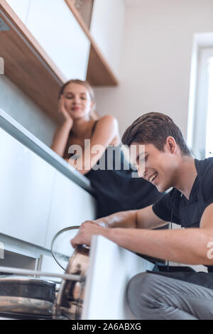Jeune homme prend les plats hors du lave-vaisselle Banque D'Images