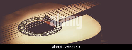 Guitare acoustique allongé sur une table en bois éclairé par un faisceau de lumière Banque D'Images