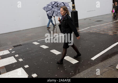 Après de fortes pluies, les londoniens et les visiteurs à pied le long de Long Acre, Covent Garden, le 24 octobre 2019, à Westminster, Londres, Angleterre. Banque D'Images