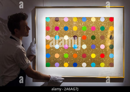 Londres, Royaume-Uni. 25 octobre 2019. Un technicien présente 'Untitled (cadeau de l'or spot)', 2008, par Damien Hirst (est. GBP5-7k). Aperçu de 'l'or : La touche Midas' chez Sotheby's à New Bond Street. Œuvres couvrant six siècles dédié à l'or sera mis en vente le 29 octobre. Crédit : Stephen Chung / Alamy Live News Banque D'Images