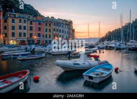 Bateaux dans le port abrité à Portofino, Ligurie Italie au coucher du soleil avec des reflets multicolores sur l'eau et de bâtiments au bord de l'italien traditionnel Banque D'Images