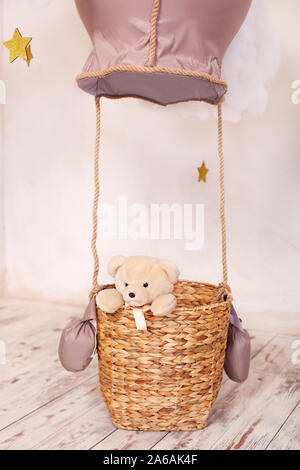 Ours en peluche assis dans le panier de montgolfière, aérostat. Décoration de la chambre d'enfants et de la salle de jeux. L'enfant joue le voyageur. Banque D'Images