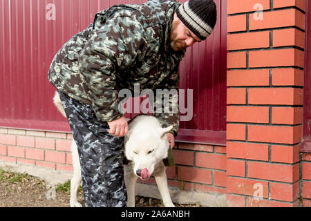 Un homme en salopette pour une promenade avec un chien Banque D'Images