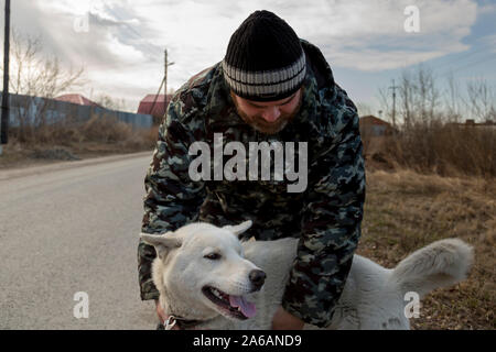 Un homme en salopette pour une promenade avec un chien Banque D'Images