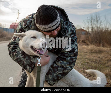 Un homme en salopette pour une promenade avec un chien Banque D'Images