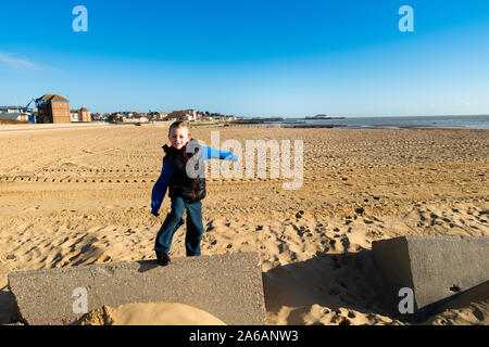 Un beau petit garçon avec TDAH, l'autisme, du syndrome d'Asperger la marche sur la plage sur une belle journée d'été, fatigué mais désireux Banque D'Images