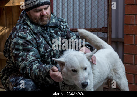 Un homme en salopette pour une promenade avec un chien Banque D'Images