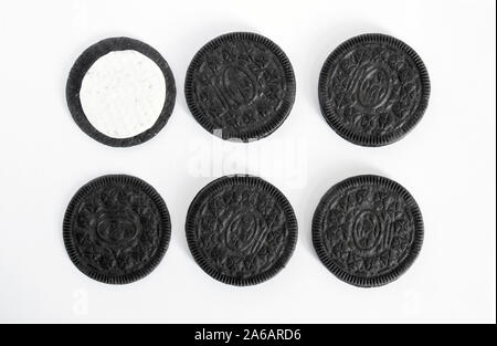 Beaucoup de noir cookies disposés en deux rangées avec un centre blanc crème sur un fond blanc. isoler. Banque D'Images