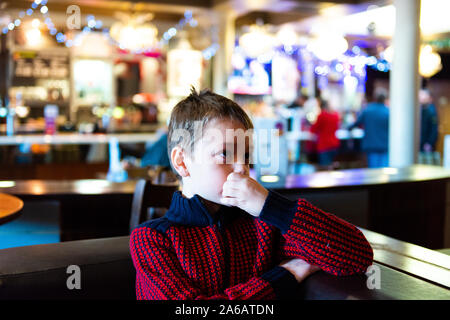 Un beau petit garçon avec le TDAH, l'autisme, syndrome d'apserger est assis dans un restaurant, pub en attente regardant la télévision à Yates à Newcastle Under Lyme Banque D'Images