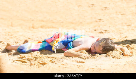 Un beau petit garçon avec TDAH, l'autisme, du syndrome d'Asperger après s'endormir sur la plage sur une belle journée d'été, épuisé, Woodup extérieure, Essex Banque D'Images