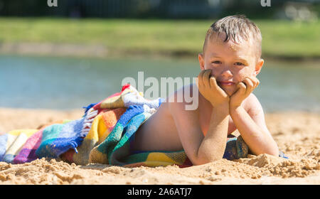 Un beau petit garçon avec TDAH, l'autisme, du syndrome d'Asperger après s'endormir sur la plage sur une belle journée d'été, épuisé, Woodup extérieure, Essex Banque D'Images