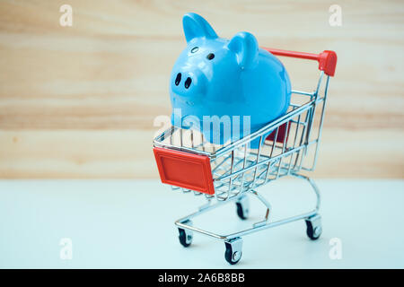 Tirelire en bleu petit jouet panier sur fond blanc et en bois. Concept de voyage d'achats. Banque D'Images