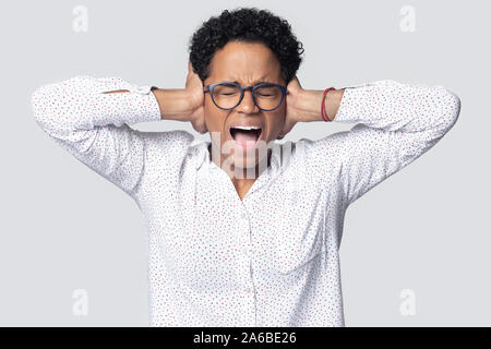 Head shot agacé African American girl couvrant les oreilles, crier fort Banque D'Images