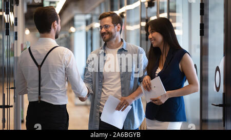 Accueil souriant collègues masculins de liaison, standing in office corridor Banque D'Images