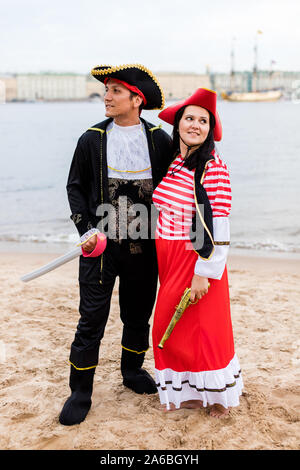 Young Caucasian man and woman in costumes pirate se tenir à côté de l'autre et de regarder dans des directions différentes sur une plage de sable. La verticale. Banque D'Images