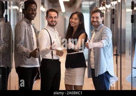 Portrait divers employés standing in office corridor, showing Thumbs up Banque D'Images