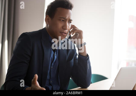 Angry black businessman conteste sur phone at office Banque D'Images