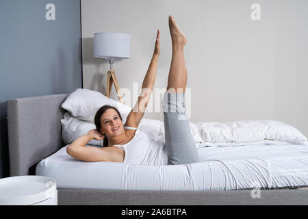 Young Woman Doing Stretching Fitness Exercise In Bed Banque D'Images