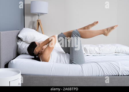 Young Woman Doing Stretching Fitness Exercise In Bed Banque D'Images