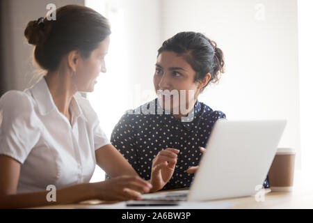 Femme senior manager helping young smiling indian intern Banque D'Images
