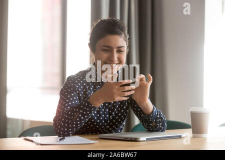 Smiling happy indian woman using smartphone ou l'appel vidéo Banque D'Images