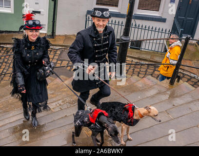 Goth couple en costume traditionnel et les chiens escalade 199 mesures pour l'abbaye de Whitby, Whitby Goth Week-end Festival, Whitby, North Yorkshire, UK, 25 Octobre 2019 Banque D'Images