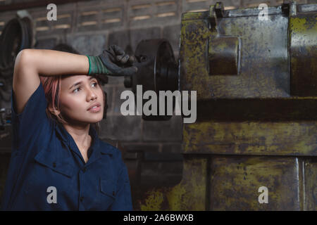 Jeune ingénieur femelle épuisé de la charge de travail dans une usine industrielle - Divers ouvrier asiatique a souligné, fatigué et pense à la vie au travail Banque D'Images