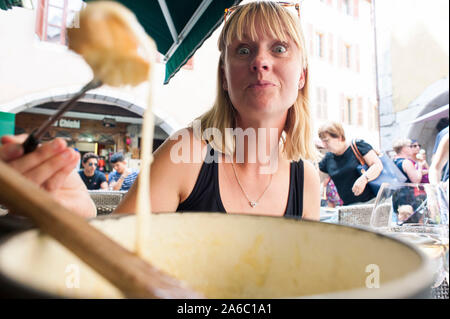 Une femme assise à l'extérieur d'un café / restaurant en france et mange la fondue de fromage fondu. Banque D'Images