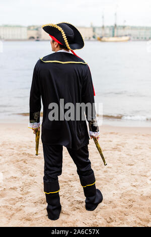 Young man in a black pirate costume abaissé les deux pistolets jouets et regarde la rivière. La verticale. Banque D'Images