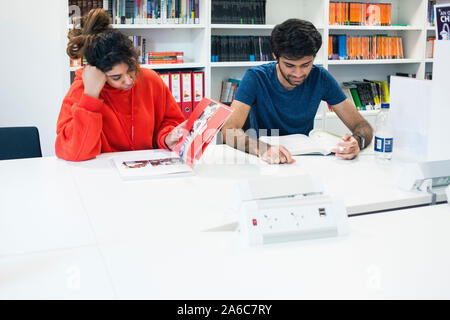 Outre-mer international étudiants assis dans une bibliothèque universitaire la lecture de livres Banque D'Images