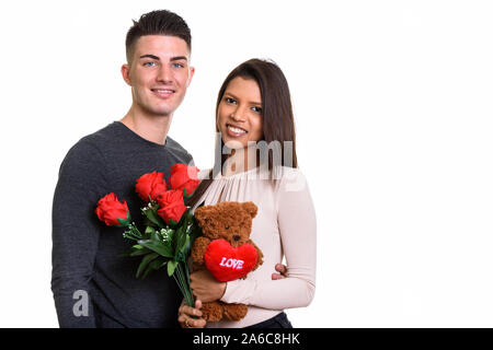 Young happy couple smiling while holding roses rouges et teddy bea Banque D'Images
