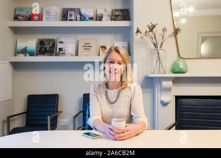 Une femme du personnel s'assoit à une table dans une salle de réunion agréable et sourit. Banque D'Images