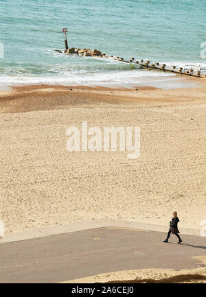 Une femme seule promenades le long de la promenade à côté de la plage de sable de Bournemouth, Angleterre. Banque D'Images