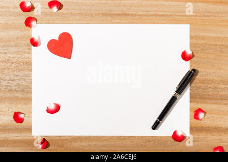 Lettre d'amour. carte blanche, en forme de coeur rouge et un stylo sur la table en bois. Mise à plat. Vue d'en haut. Des maquettes. Concept d'amour Banque D'Images