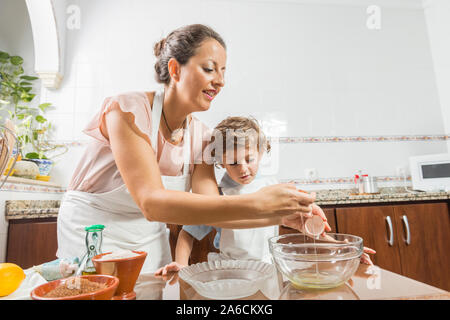 Une femme et un enfant d'oeufs de craquage pour faire un gâteau fait maison. Banque D'Images