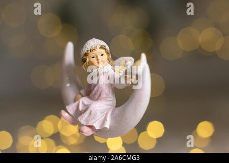 Figurines décoratives d'un thème de Noël. Statuette d'un ange sur un croissant de lune. Décoration d'arbre de Noël. Décor de fête, chaud bokeh lights Banque D'Images