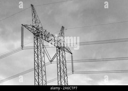 Un angle faible et en noir et blanc vue d'un pylône électrique, cadre treillis en acier soutenant la tour de l'électricité à haute tension câbles avec prix pour type. Banque D'Images