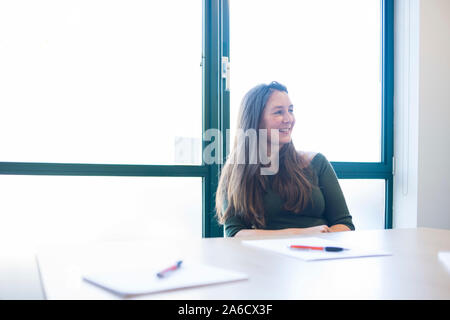 Une femme blanche est assis autour d'une table de réunion dans un bureau lumineux avec plein de fenêtres dans une combinaison intelligente Banque D'Images