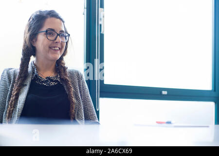 Une femme blanche est assis autour d'une table de réunion dans un bureau lumineux avec plein de fenêtres dans une combinaison intelligente Banque D'Images