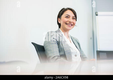 Une femme blanche est assis autour d'une table de réunion dans un bureau lumineux avec plein de fenêtres dans une combinaison intelligente Banque D'Images