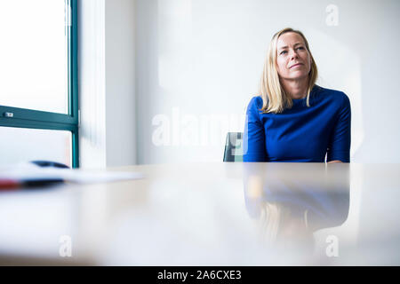 Une femme blanche est assis autour d'une table de réunion dans un bureau lumineux avec plein de fenêtres dans une combinaison intelligente Banque D'Images