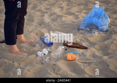 Jeune Volontaire est la marche avec sac à déchets le long d'une plage de la rivière sale et le nettoyage de la corbeille. Les gens et l'écologie. Close-up. Banque D'Images