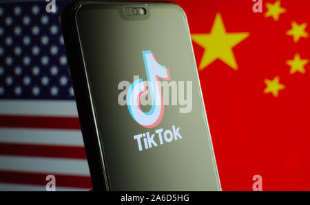 TikTok app logo sur un écran de smartphone et de drapeaux de la Chine et des États-Unis sur l'arrière-plan flou. L'app est dans le centre d'entre nous - Chine les tensions. Banque D'Images