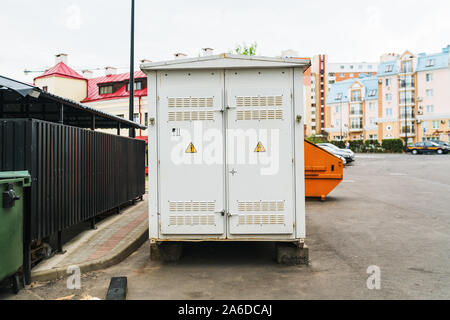 Transformateur électrique gris prix immeuble avec portes blanches et jaunes, les signes de danger dans la ville sur fond de ciel bleu Banque D'Images